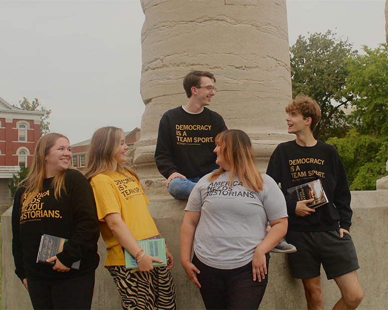 Five undergraduate students wearing shirts that say "Democracy is a Team Sport" and "America Needs Historians."
