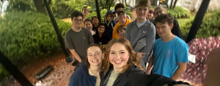 A group of students take a selfie in a garden.