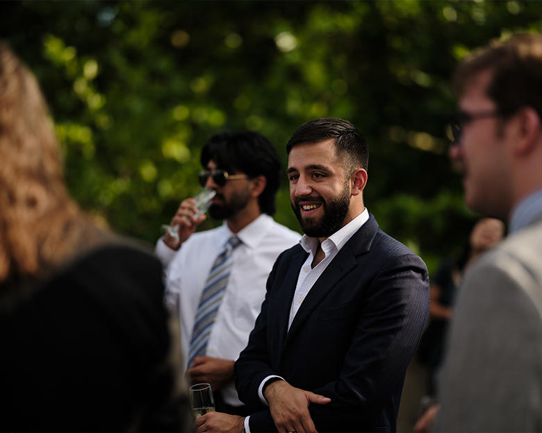 A man talks with others at an outdoor gathering.