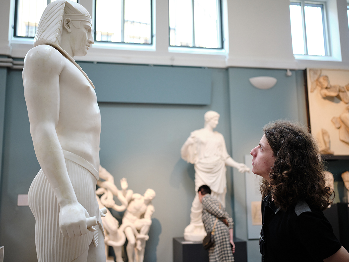 A student views a statue of an Egyptian pharaoh.