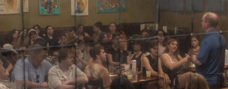 Students at a dinner lecture reflected in the restaurant mirror.