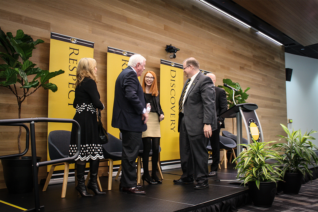 Rich and Nancy Kinder speak with three other people on a stage.