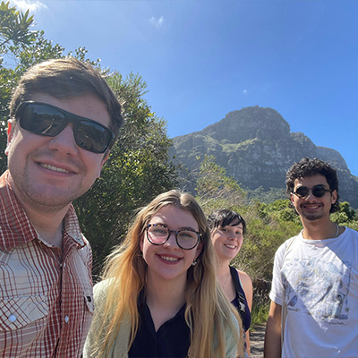 Four students take a selfie in front of a mountain in South Africa.