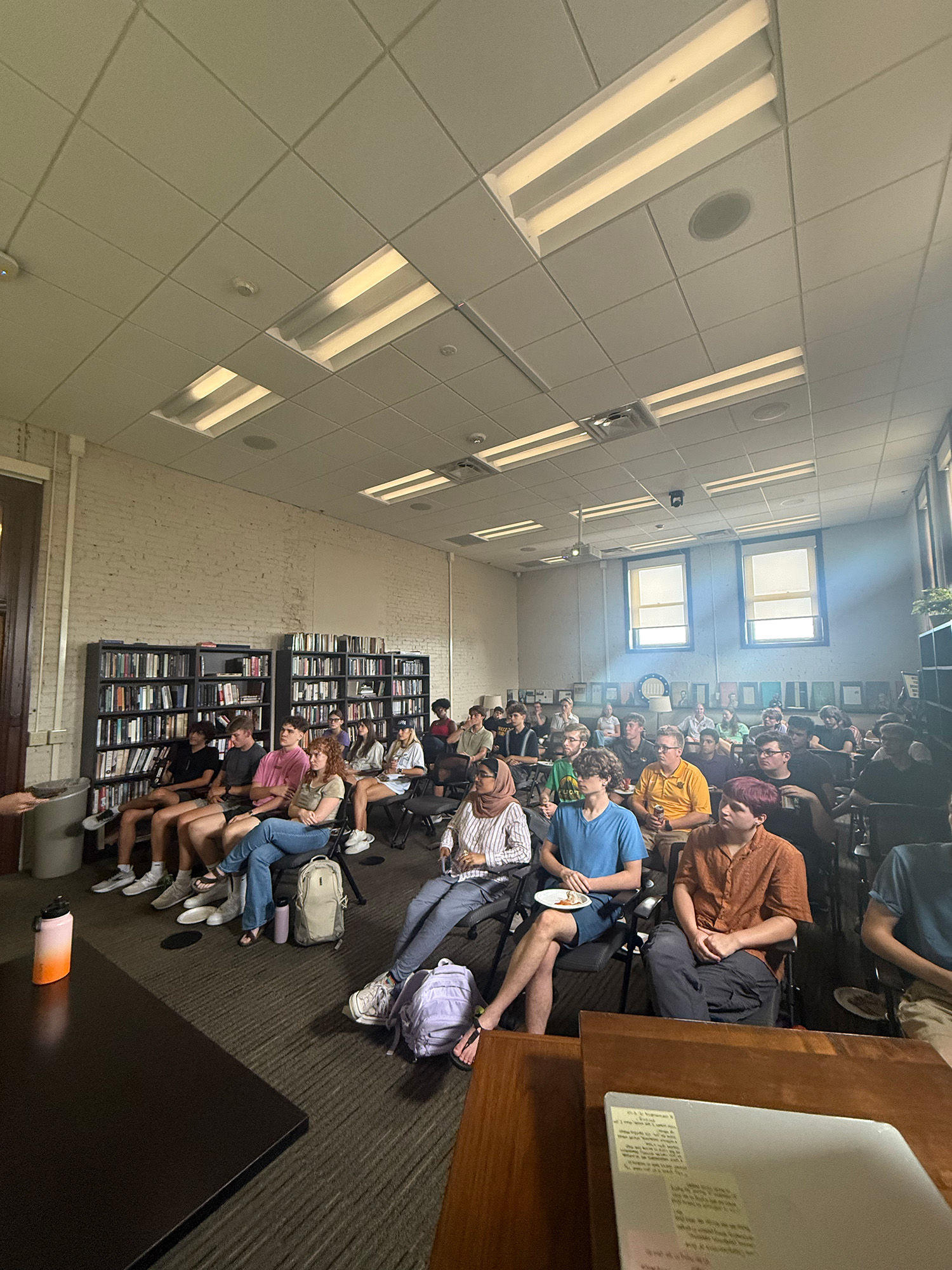 A group of students sit and listen to an off-camera speaker.