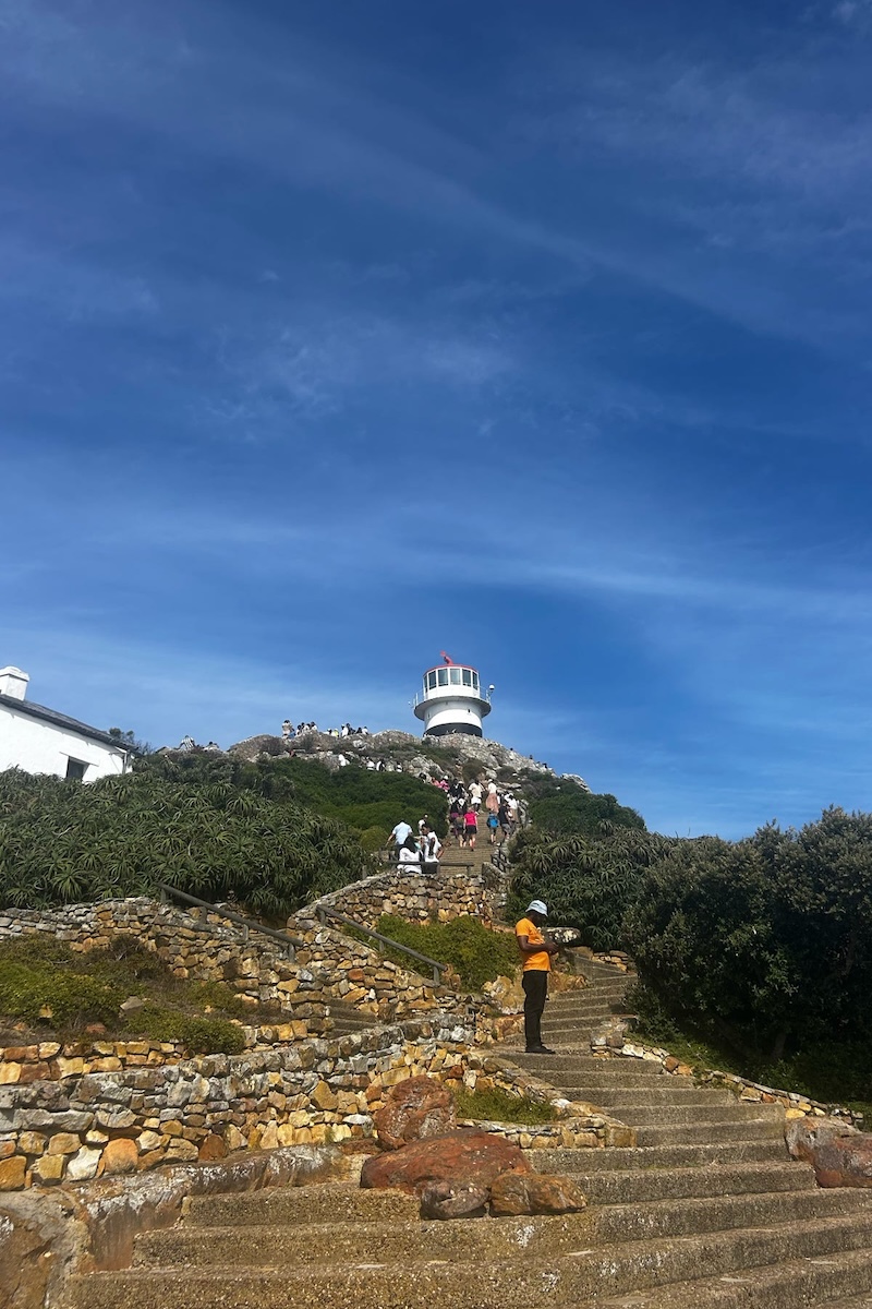 Students ascend a mountain atop which sits one of Cape Town's historic lighthouses.
