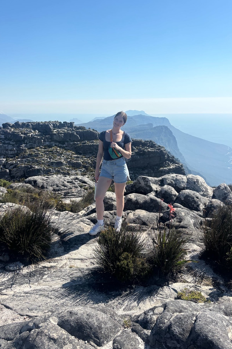 A student standing on a mountaintop in Cape Town, South Africa