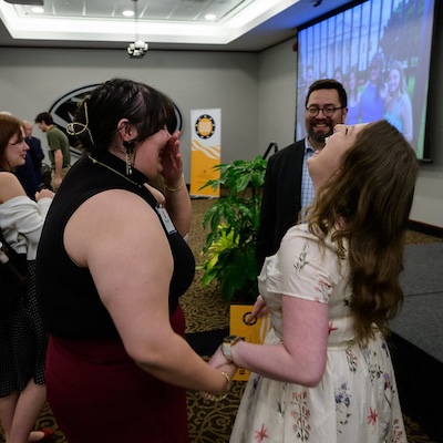 Two undergraduate students tilt their heads back in laughter. 