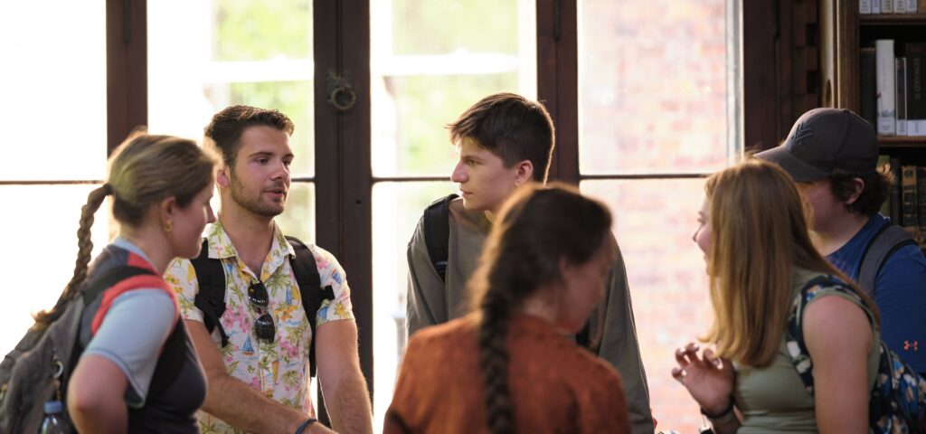 Students in conversation in front of a library window.