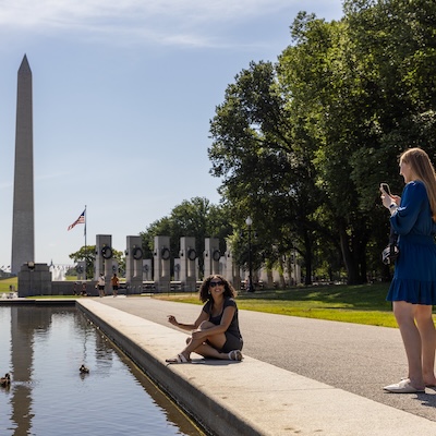 A student sits beside the Lincoln Memorial Reflecting Pool, idly chatting with a friend