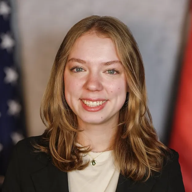 A young woman poses for a headshot between the US and Missouri flags.