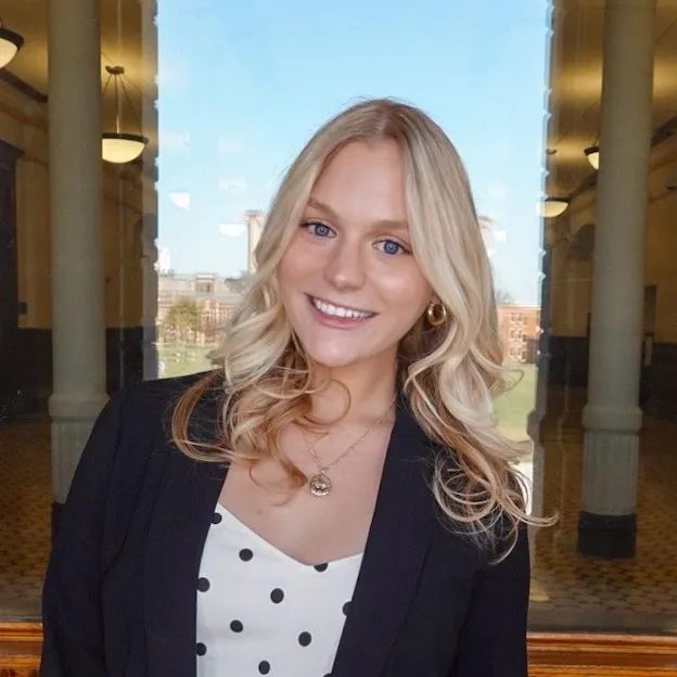 A young woman with blonde hair poses for a professional headshot on the veranda of Mizzou's Jesse Hall