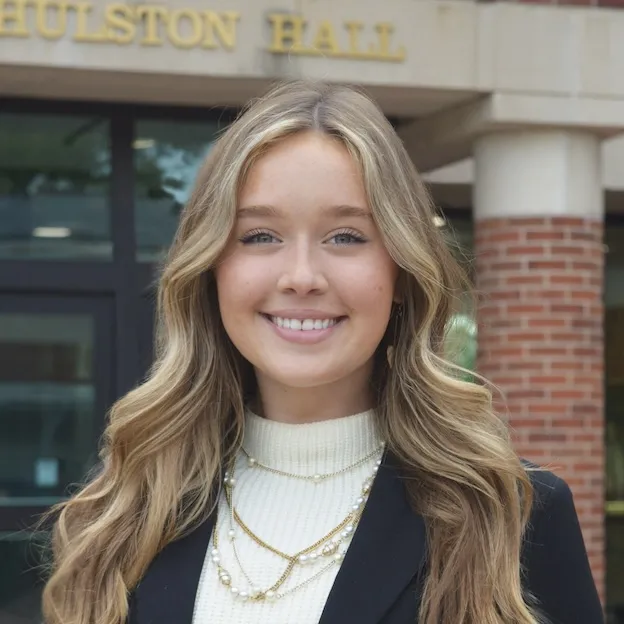 A young woman with blonde hair poses for a professional headshot in front of the University of Missouri Law School
