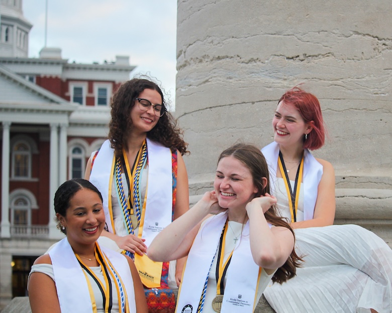 Four college seniors gather at the Columns on Mizzou's campus for their graduation photos