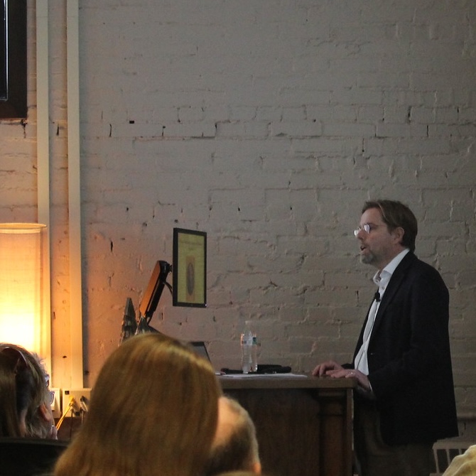 A bearded professor gives a talk in a small lecture hall.