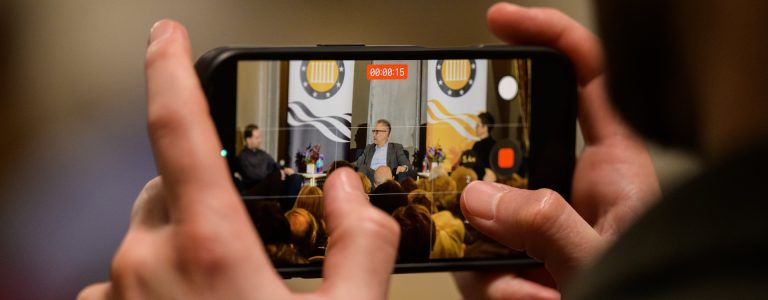 A close up image of someone filming a lecture on their phone